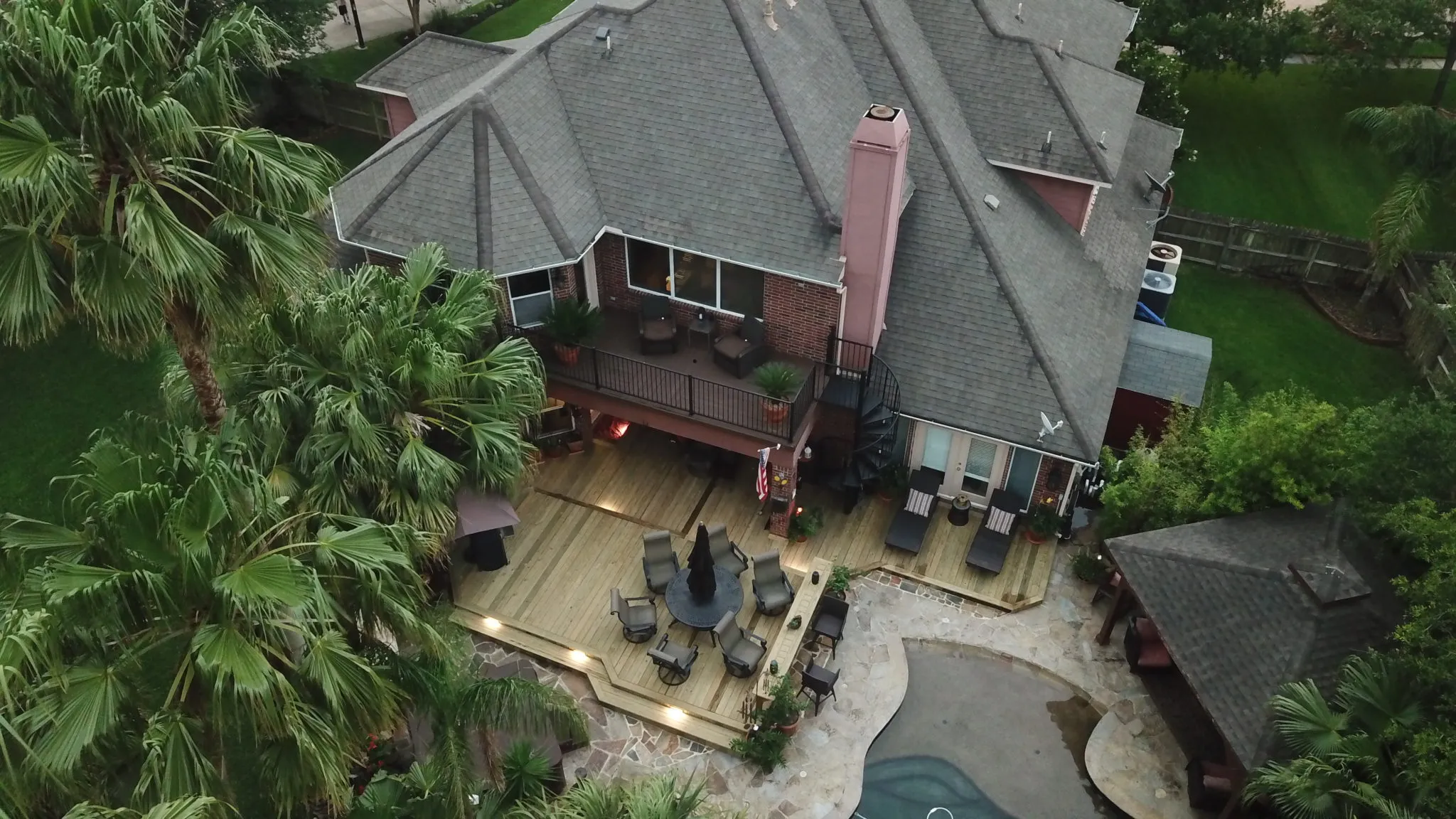 a beautifully designed residential deck made with custom wood, featuring a spacious outdoor seating area, railing, and steps, providing a perfect space for relaxation and entertainment.