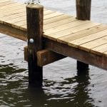 Close up of a deck's pressure treated pilings in water.