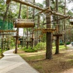 Adventure climbing high wire park people on course in mountain helmet and safety equipment