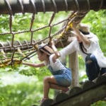 Mother and daughter playing on rope course.